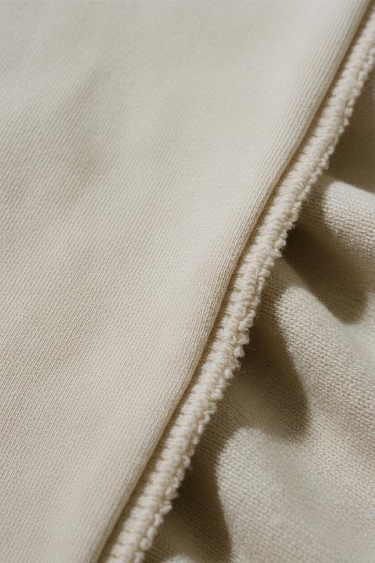 French terry fabric macro, smooth exterior face and uncut looped interior visible at fold, stone off-white colourway, soft diffused light