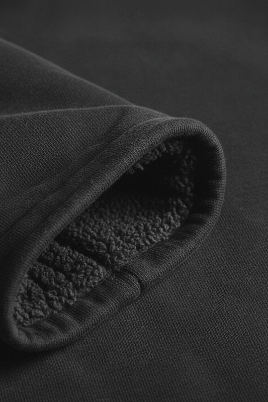 400gsm loop-back fleece fabric macro, smooth exterior and dense looped interior visible at fold, washed black heavyweight cotton hoodie