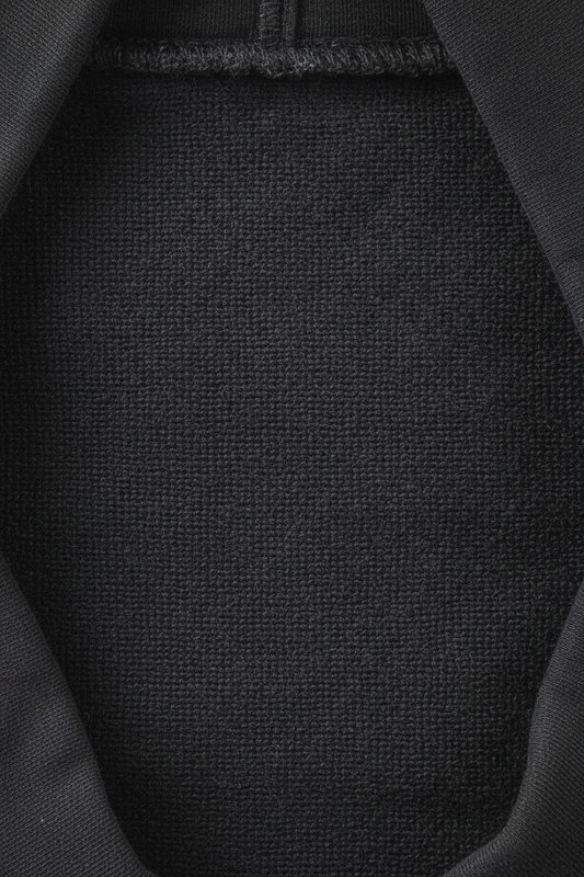 Heavyweight washed black hoodie draped over brutalist concrete bench — echelonn. aegis. 400gsm loop-back fleece interior visible