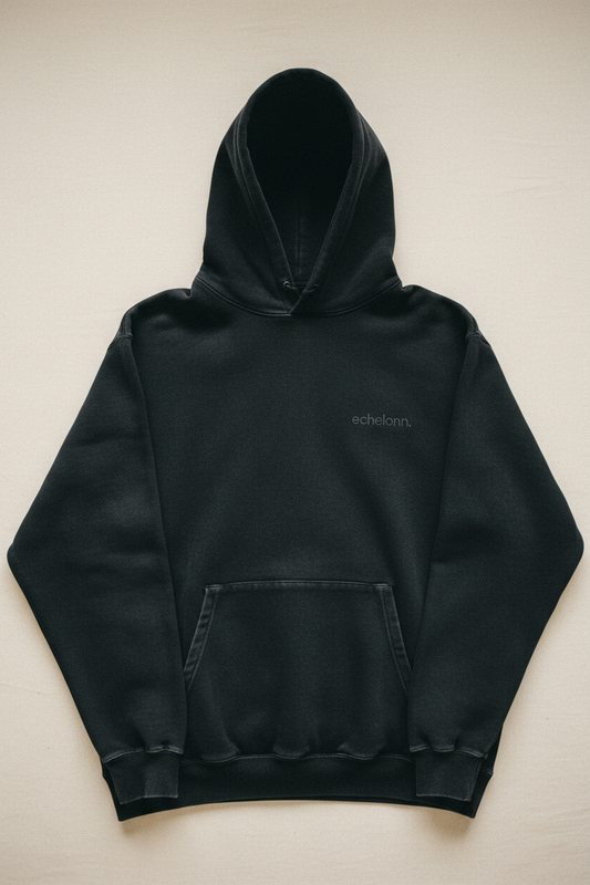 echelonn. aegis. heavyweight hoodie flat lay — washed black 400gsm loop-back fleece, enzyme-washed, tonal echelonn. wordmark on left chest
